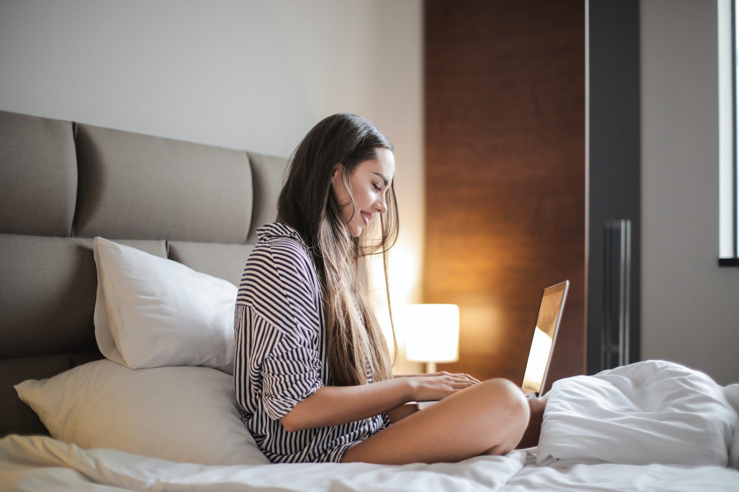 Young women with laptop in bed