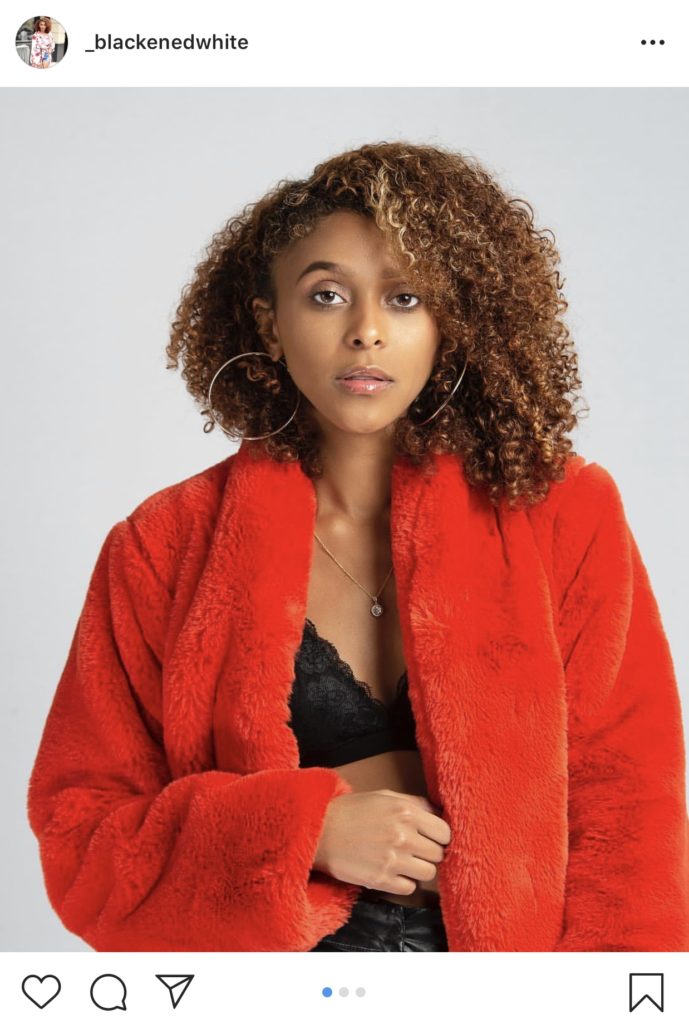 A woman in a red jacket with gold hoop earrings. 